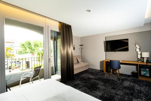 Habitación de hotel con cama, escritorio y TV. en Fac & Spera -Hôtel & Spa en Tain-lʼHermitage