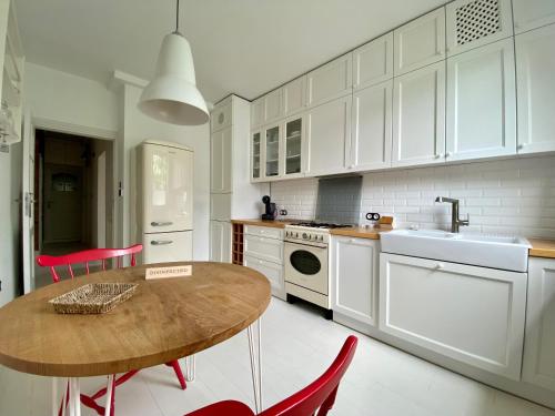 a kitchen with white cabinets and a wooden table at Chic Apartment in vibrant area - National Stadium - Saska Kępa in Warsaw