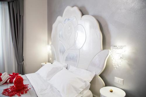 ein Schlafzimmer mit einem weißen Bett mit einer Blume an der Wand in der Unterkunft Il Teatro B&B in Marina di Gioiosa Ionica