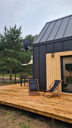 a black building with two chairs on a wooden deck at Sasinko Mini in Sasino