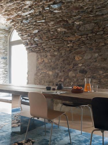 a dining room with a stone wall and a table and chairs at Casa Olea Hotel in Cremia
