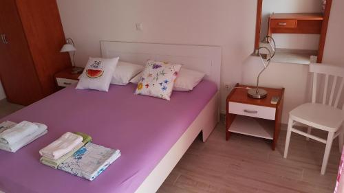 a purple bed in a small room with a chair at Apartments Boćin Rosso in Hvar