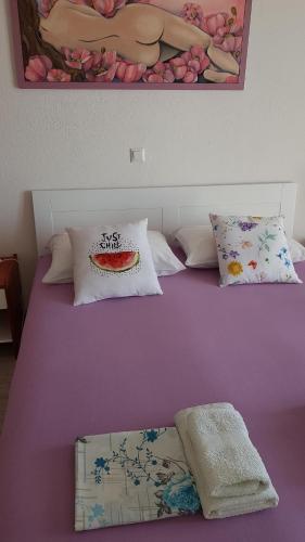 a purple bed with pillows and a painting on the wall at Apartments Boćin Rosso in Hvar