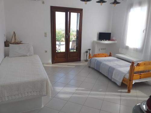 a white bedroom with a bed and a window at Naxian vacation with sea view in Naxos Chora