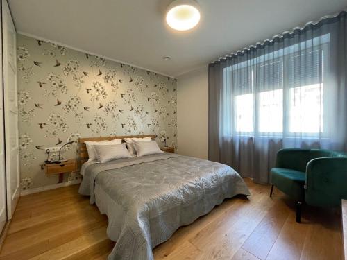 a bedroom with a bed and a green chair at Niidupuu Apartment in Kuressaare