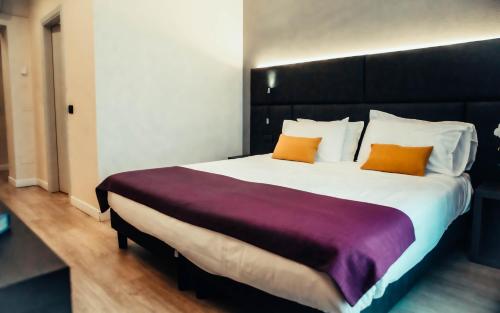 a bedroom with a large bed with two orange pillows at Hotel Benaco in Desenzano del Garda