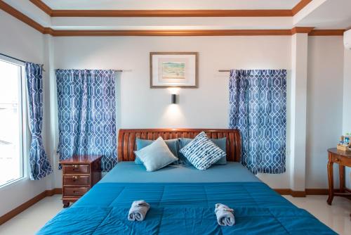 a bedroom with a blue bed with shoes on it at Baan Virog Koh Larn in Ko Larn