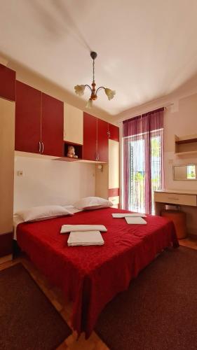a bedroom with a large red bed with towels on it at Apartments Crljen in Brodarica