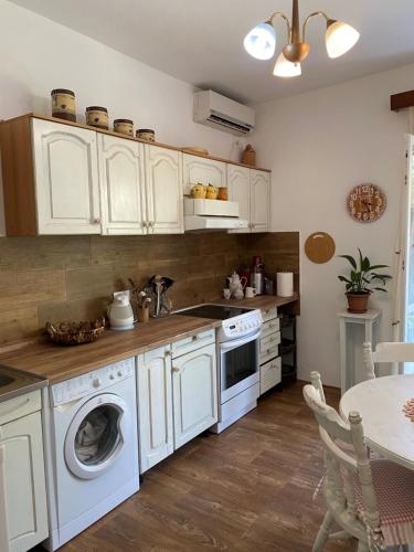 cocina con armarios blancos y lavadora en M&B apartment, en Kotor
