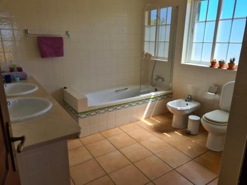 a bathroom with two sinks and a tub and a toilet at Casa dos Ventos in Olhão