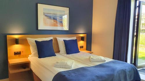 a bedroom with a large bed with blue pillows at Willa Abrazja - wypoczynek dla dorosłych in Jastrzębia Góra