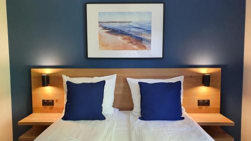 a bedroom with a bed with two blue pillows at Willa Abrazja - wypoczynek dla dorosłych in Jastrzębia Góra