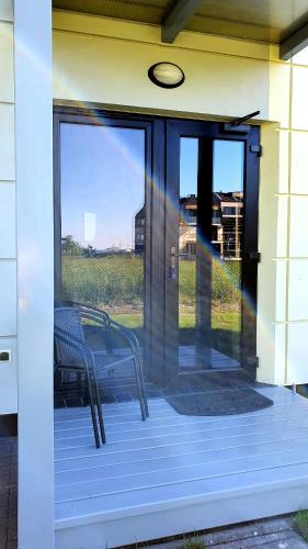 a glass door of a house with a chair on a porch at Willa Abrazja - wypoczynek dla dorosłych in Jastrzębia Góra