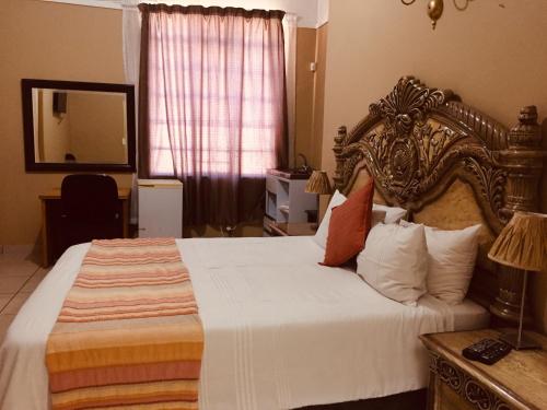 1 dormitorio con 1 cama grande y espejo en Chancellors Court Guest House en Pretoria
