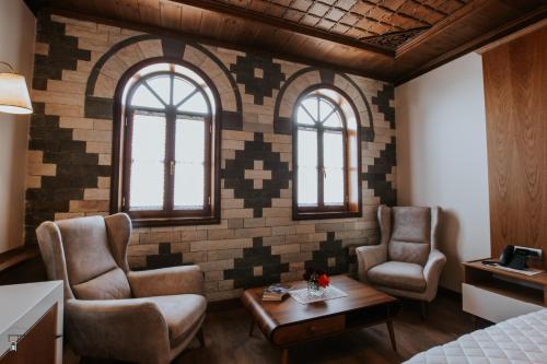 a room with two chairs and a table and two windows at KERCULLA Resort in Gjirokastër