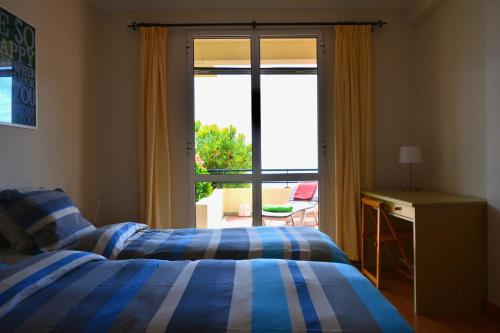 a bedroom with a bed and a sliding glass door at Jardim do Arco "Esmee" in Arco da Calheta