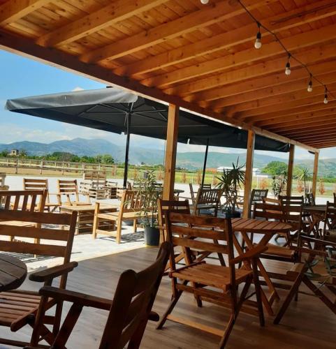 a group of wooden tables and chairs with umbrellas at House of Horses Shtepia e Kuajve in Korçë