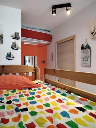- une chambre avec une couette colorée sur un lit dans l'établissement Charmant studio Bord de mer Plage Ste Marguerite Pornichet, à Pornichet
