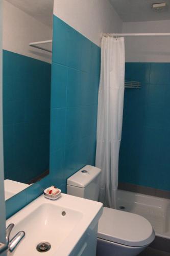 a blue bathroom with a white toilet and a sink at Lugar da Lourida in Caminha
