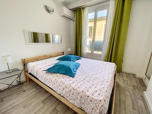 une chambre avec un lit avec des oreillers bleus et une fenêtre dans l'établissement Mon Gîte Sainte Marie Climatisé, à Sète