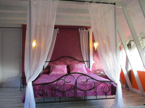 a purple bed with pink pillows and curtains at Le Clos du Chêne in Langon