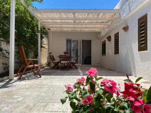 eine Terrasse mit rosa Blumen und einem Holztisch in der Unterkunft Casa Alfonsa in Villanova di Ostuni