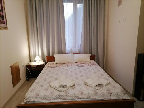 a bedroom with a bed with two pillows and a window at White home-apartament in Burgas City