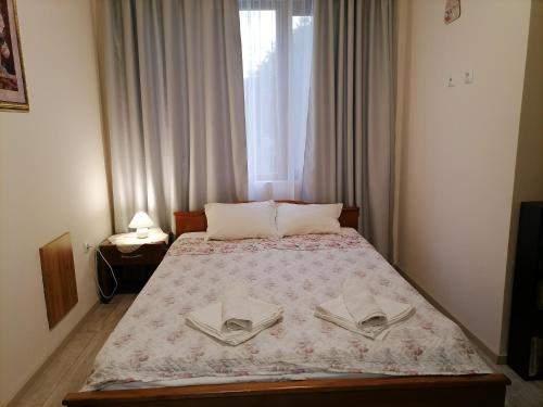 a bedroom with a bed with two pillows and a window at White home-apartament in Burgas