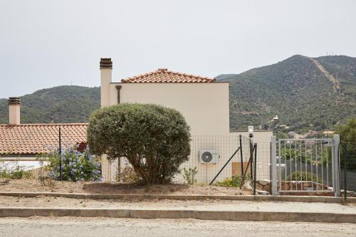 ein weißes Haus mit einem Zaun und einem Baum in der Unterkunft Casa Chersonnesus in Teulada