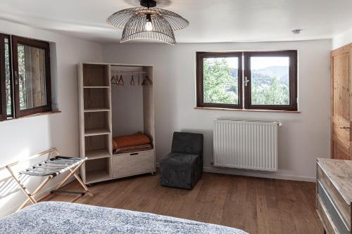 a bedroom with a bed and a chair and windows at Le Tintinnabule in Villard-de-Lans