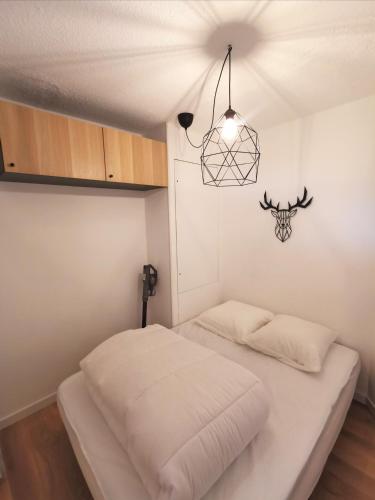 - une chambre avec un lit blanc et un lustre dans l'établissement Chaleureux T2 La Tania Courchevel pieds des pistes, à Courchevel