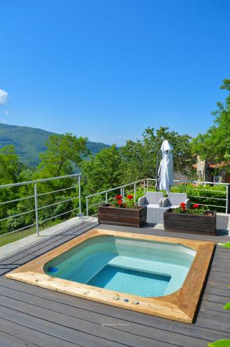 a swimming pool on a deck with a table and flowers at Agriturismo Vezzano in Chiusi della Verna