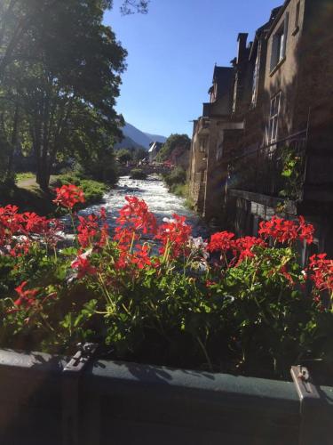 a river with red flowers next to some buildings at Arreau appartement 4 personnes in Arreau