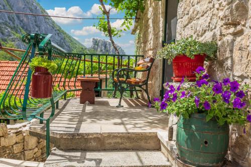 a balcony with pots of flowers and a view of mountains at Mini stone house in Omiš