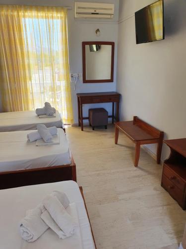 a room with two beds and a desk and a mirror at Rivulet Studios in Laganas