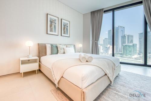 Exquisite 1BR at The Address Residences in JBR by Deluxe Holiday Homes في دبي: غرفة نوم بسرير كبير ونافذة كبيرة
