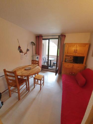 uma sala de estar com uma mesa e um sofá vermelho em Studio à la montagne meublé et entièrement équipé em Bellevaux