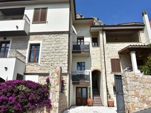 un bâtiment dans un village aux fleurs violettes dans l'établissement Villa Janas, à Baunei