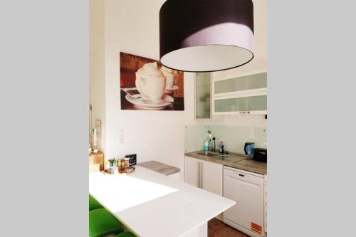 una cocina con encimeras blancas y una lámpara grande en Apartment in Neudorf Nahe DU Zentrum und Uni/Zoo, en Duisburg