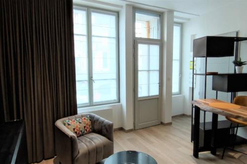 un salon avec une chaise et une table dans l'établissement Appartement T2 Centre-ville Entièrement rénové, à Reims