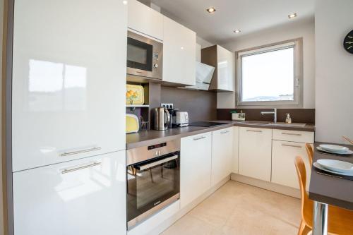 une cuisine avec des armoires blanches et une fenêtre dans l'établissement 2-Bedroom apartment in Grand Hotel, à Cannes