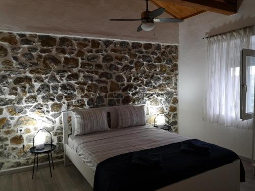 a bed in a room with a stone wall at Mandal Cottage in Samothraki