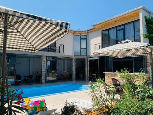 una imagen de una casa con piscina y sombrillas en Guest House Smile en Kobuleti