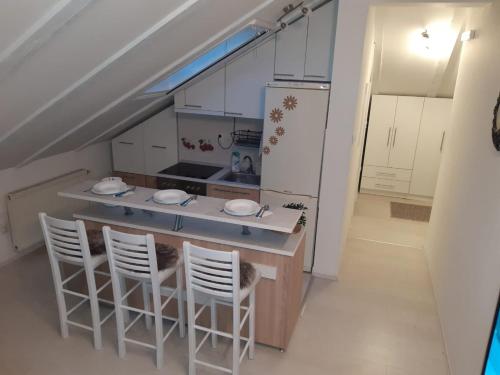 een keuken met een aanrecht met stoelen en een koelkast bij Apartman Joy in Pasuljište