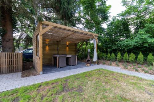 a wooden pavilion with a dog sitting under it at Vakantiehuis Salamander Maasmechelen in Maasmechelen