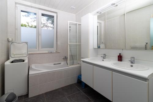a bathroom with two sinks and a tub and two mirrors at Vakantiehuis Salamander Maasmechelen in Maasmechelen