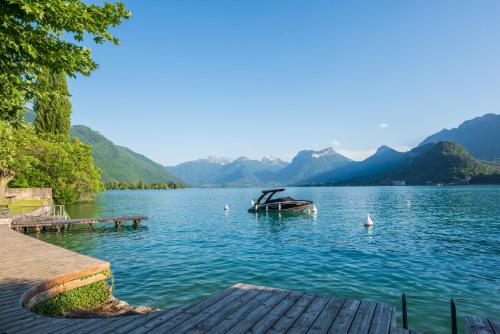 a boat on a lake with mountains in the background at Hôtel Beau Site Talloires B SPA in Talloires