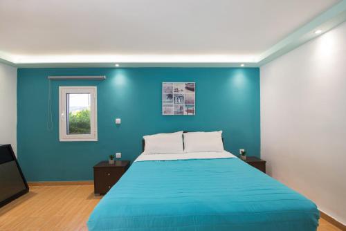 a blue bedroom with a bed and a window at Villa PANGALIS Romantica in Kato Pavliana