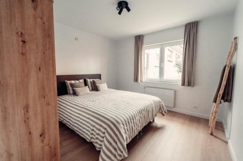 a bedroom with a bed with a striped blanket at Floride, The Perfect Getaway in Koksijde