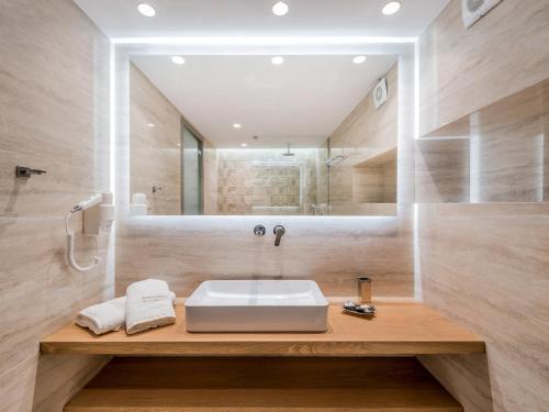 uma casa de banho com um lavatório branco e um espelho. em Katerina Palace Hotel em Argasi